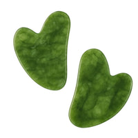 Two green jade gua sha tools on a white background
